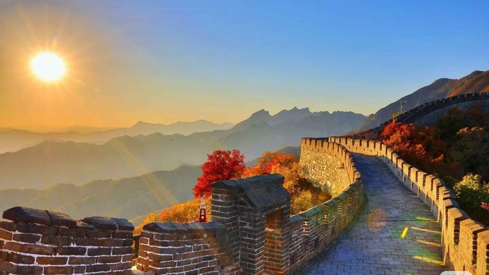 The Great Wall of China with autumn foliage, mountains in the background, and the sun setting. 4