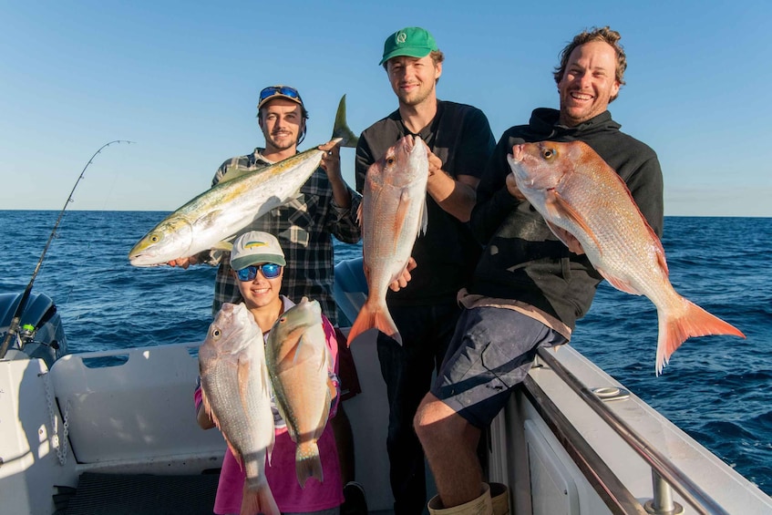 Four people on a boat holding fish. 1