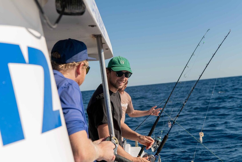 Two people fishing on a boat in the ocean. 1