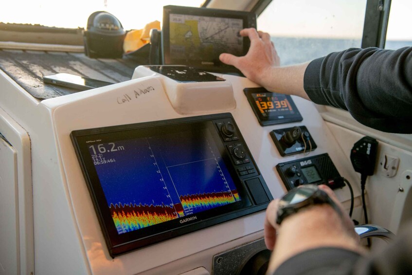 A Garmin GPS device with a digital display, a handheld GPS device, and a radio on a boat's control panel. 4