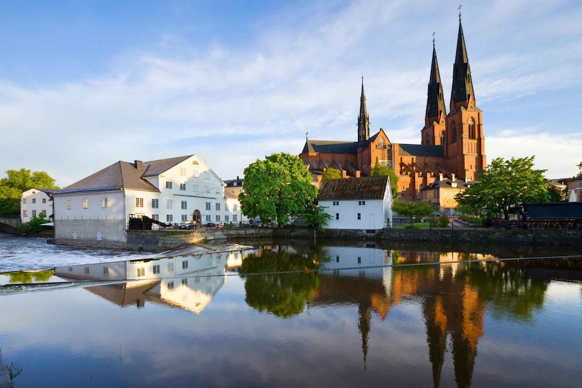A river reflecting buildings and a church with two spires. 5