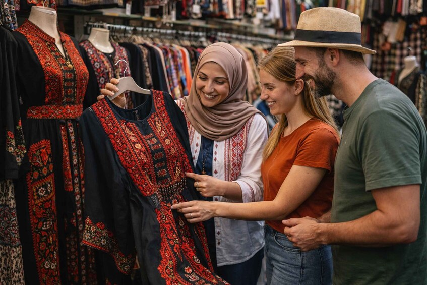 A person examining a black dress with red embroidery in a clothing store. 1