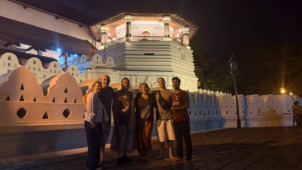 A group of people standing in front of a historic building with a large, illuminated tower. 1