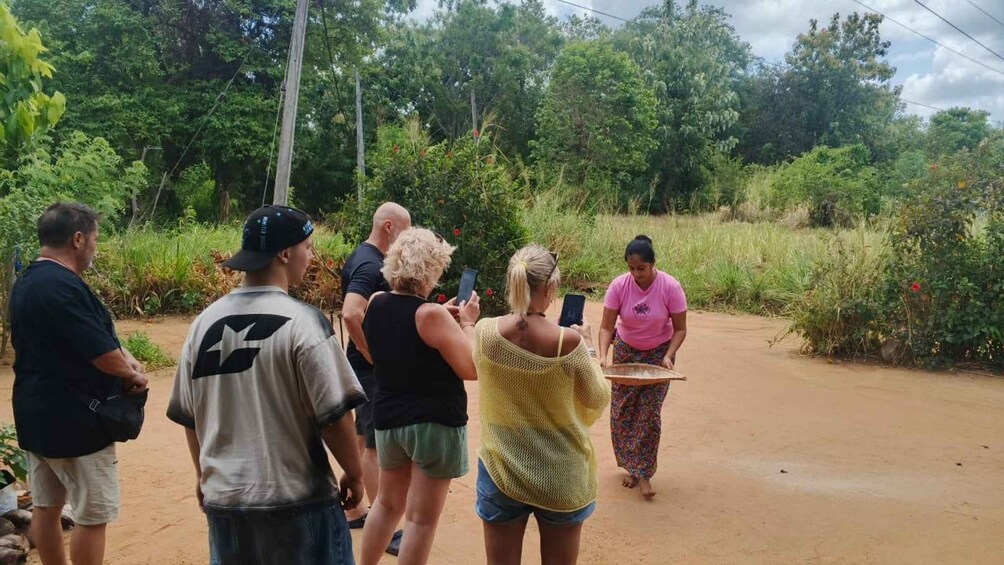 A group of people standing on a dirt path surrounded by greenery. 3