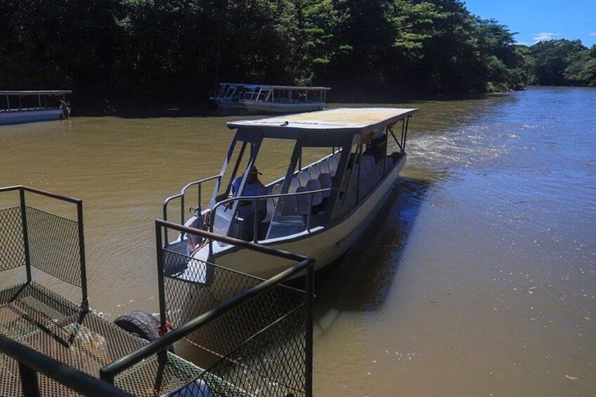 A boat docked at a pier with a forested riverbank in the background. 5
