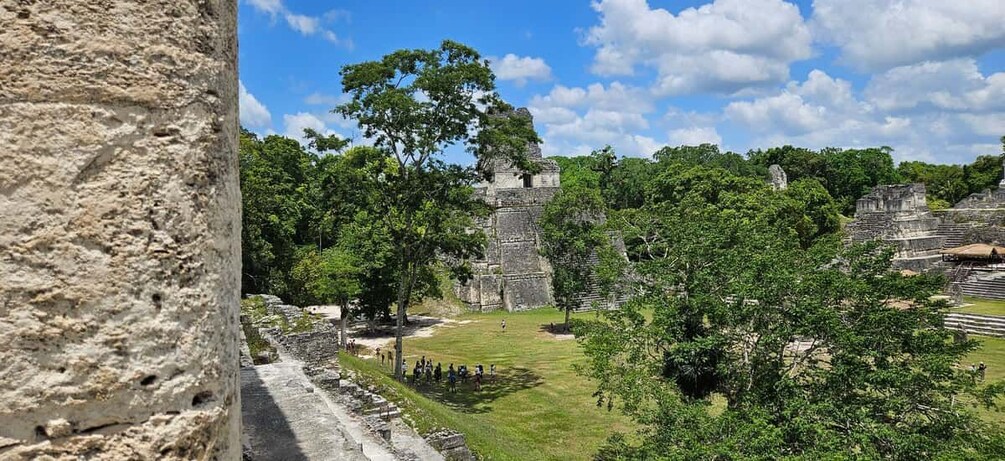 Ancient Mayan ruins with large stone structures and a grassy area. 1