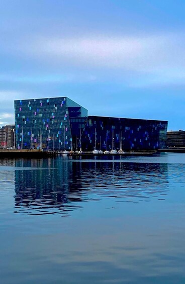 A modern building with a glass facade near a body of water. 1