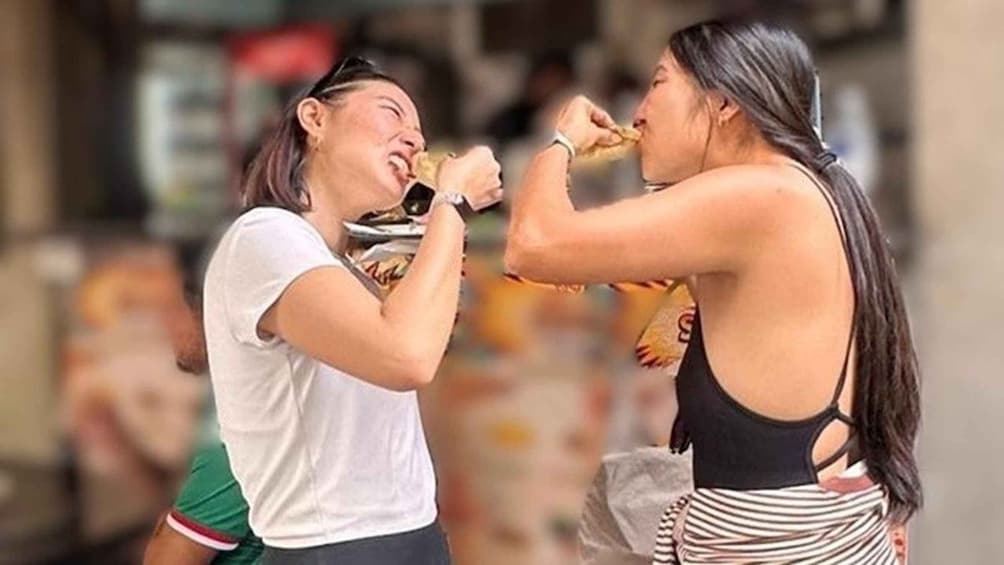 Two people in a casual outdoor setting, one wearing a white shirt and the other in a black top with a striped skirt. 1