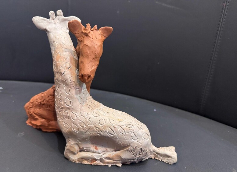 A sculpture of two giraffes on a gray surface. 2