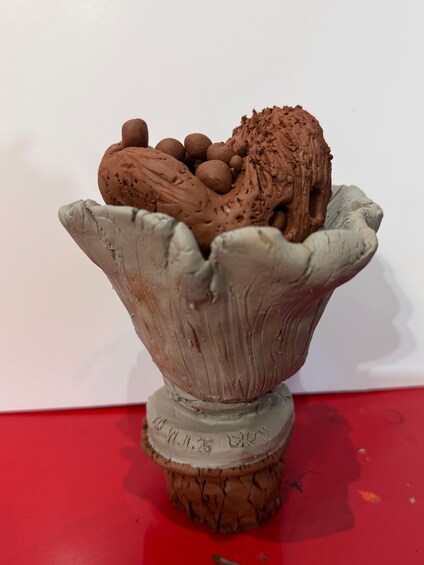 A clay sculpture of a bowl with chocolate ice cream and eggs on top. 3