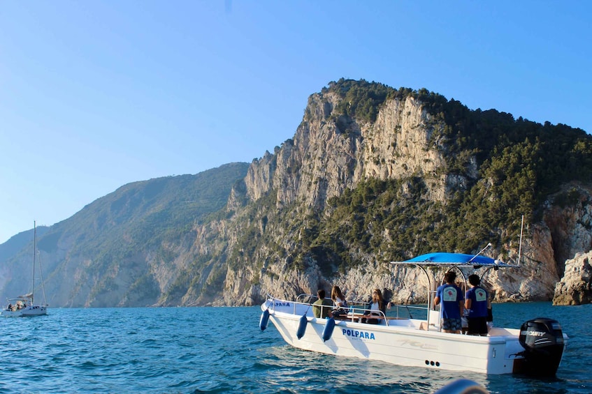 A boat named 'POLPARA' with people on board, sailing near a rocky coastline. 2