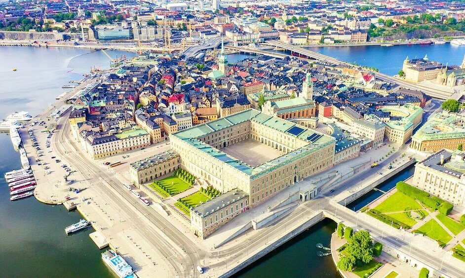 An aerial view of a city with a prominent historic building, a river, and a harbor with boats. 5