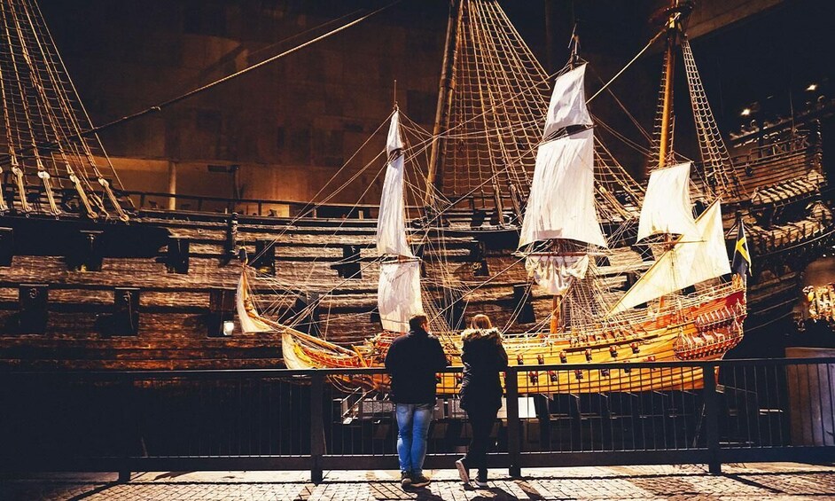 A large ship on display, with two people observing it. 4