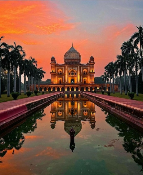 A grand building with a central dome and two towers, surrounded by palm trees and reflecting in a body of water. 1