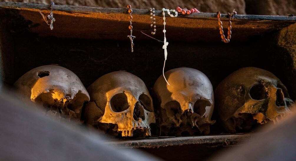 Four skulls with chains and beads in a wooden box. 1