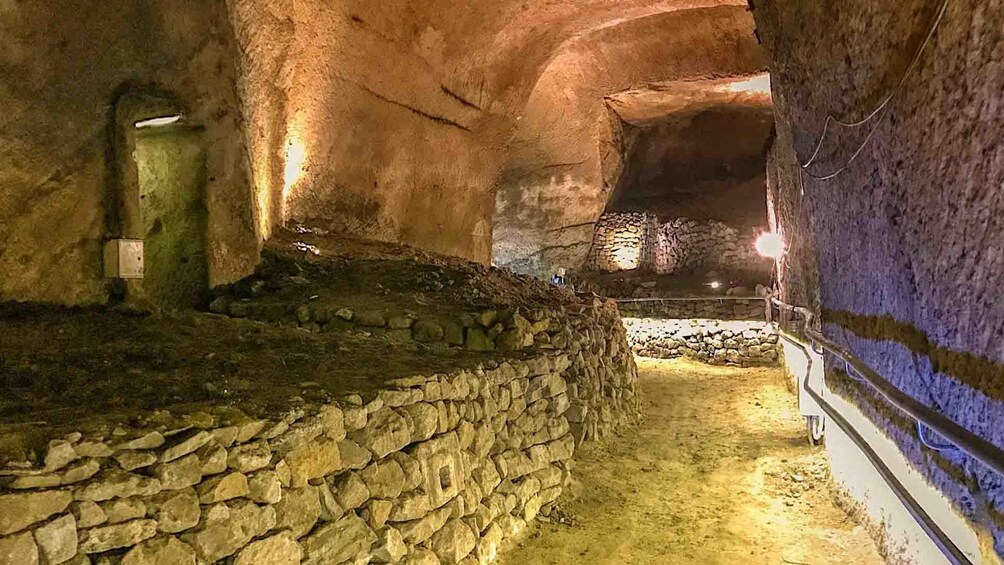 An underground passage with stone walls and a stone bench. 3
