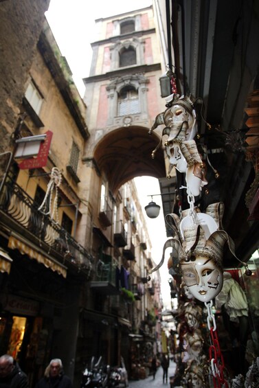 A narrow street with ornate masks hanging from a building. 4