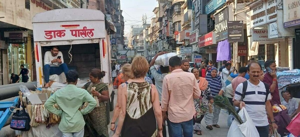 A busy street with people walking and a man sitting on a cart. 5