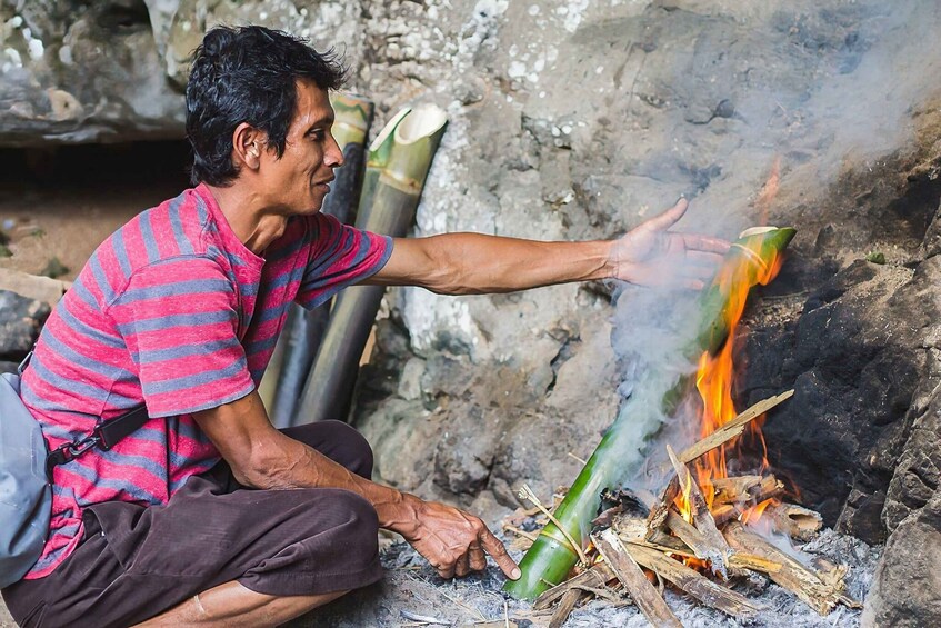 A person sitting by a fire, with a green container and a metal pot nearby. 5