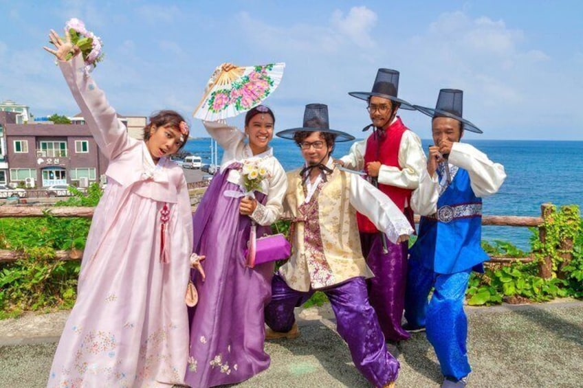 A group of people in traditional costumes by a seaside with buildings in the background. 2