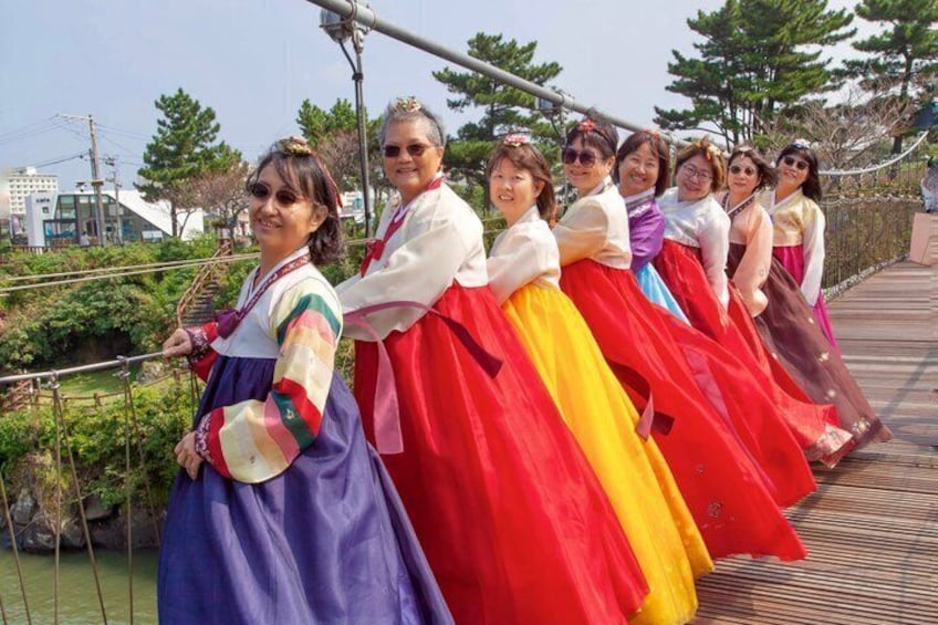 A group of people in colorful traditional dresses on a wooden bridge. 3