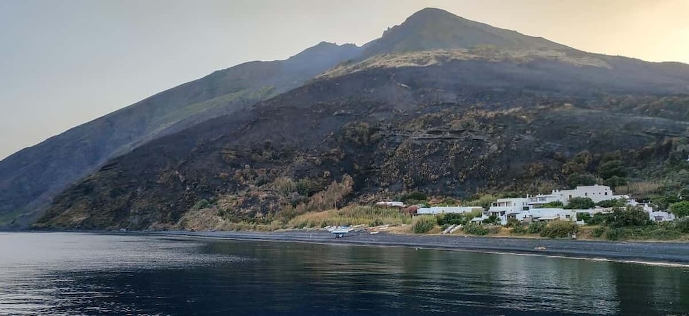 A coastal landscape with a mountain, a body of water, and a cluster of white buildings. 4