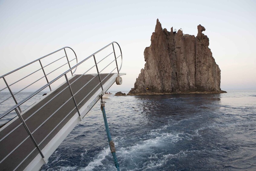 A boat's railing, choppy sea, and a rocky cliff. 5