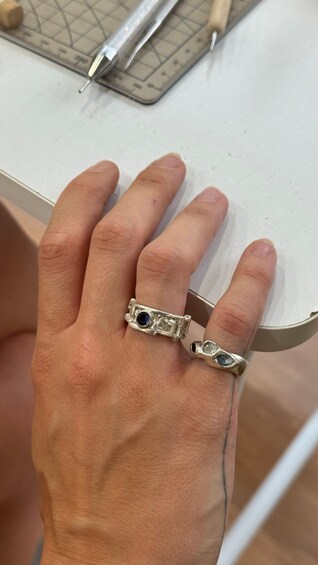 A hand wearing a silver ring with a blue gemstone. 3
