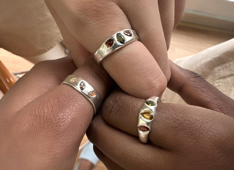 Two hands wearing silver rings with gemstones. 1
