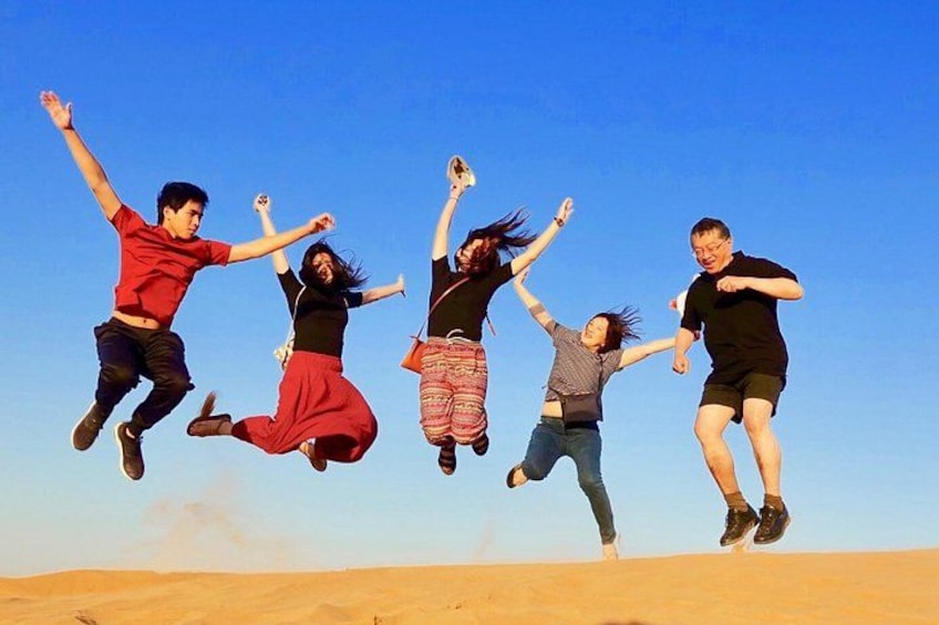 A group of people jumping in the air in a desert landscape. 2
