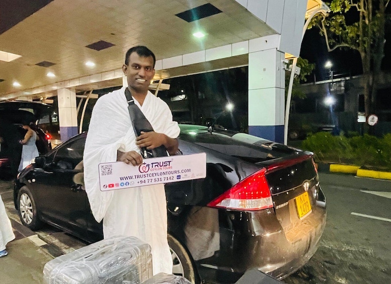 A man standing next to a black car at a gas station. 2