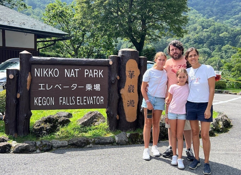 A family standing in front of a sign for Nikko Nat Park's Kegon Falls Elevator. 1