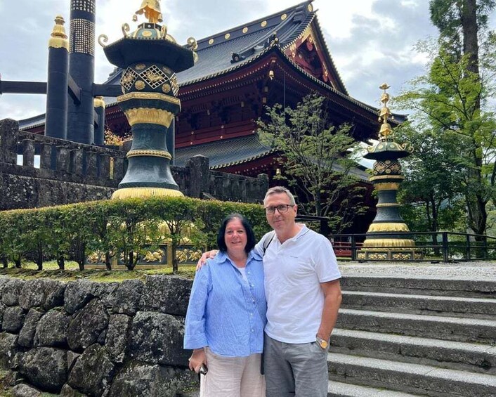 A traditional Japanese temple with ornate golden statues and a stone wall in the foreground. 4