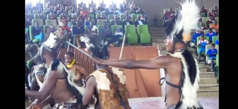 A cultural performance with participants in traditional attire and feathered headdresses. 1