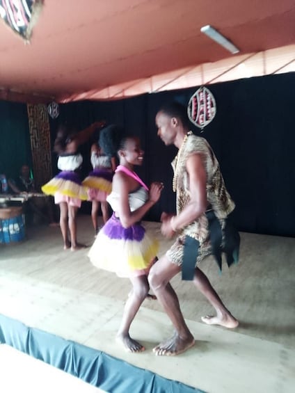 A stage with a person in traditional attire and children in colorful costumes. 2
