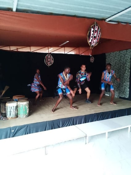 A stage with four people performing, surrounded by traditional drums and cultural decorations. 3