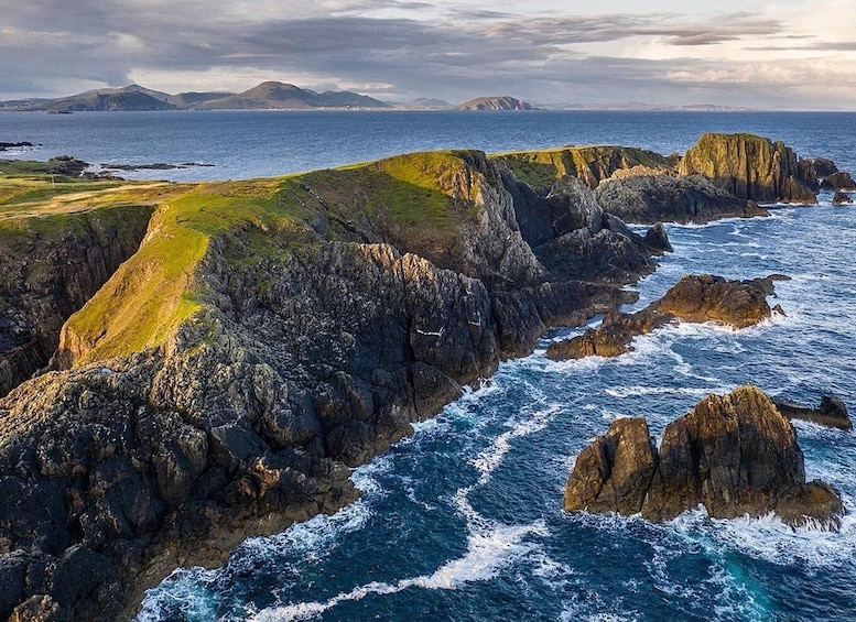 A rugged coastline with steep cliffs, rocky outcrops, and a turbulent sea. 3
