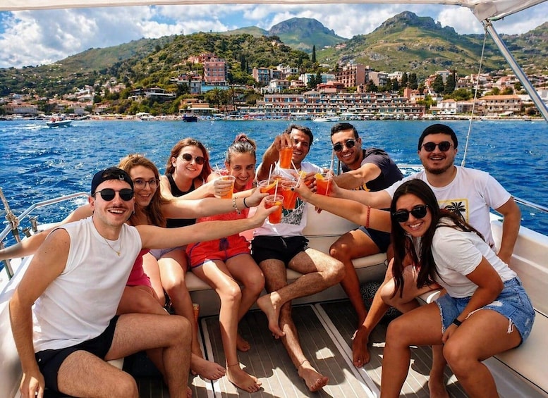 A group of people on a boat with a coastal town and hills in the background. 1