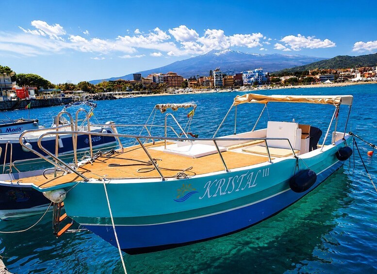 A boat named 'KRISTAL III' docked at a marina with a clear blue sky and a mountain in the background. 2