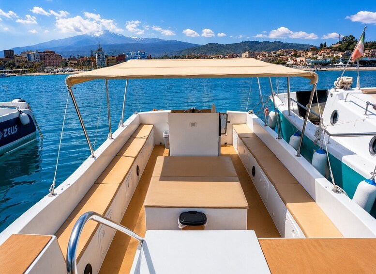 A boat with a beige canopy, a white and blue Zodiac boat, and a mountainous landscape in the background. 3