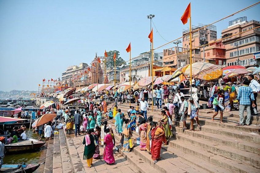 A crowded riverside with people walking and boats. 3