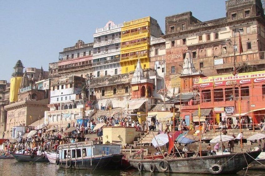 A busy riverside with boats, people, and colorful buildings. 1