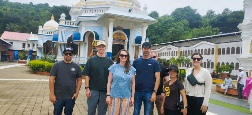 Eine Gruppe von Menschen steht vor einem Tempel mit Kuppeldächern und Säulen. 1