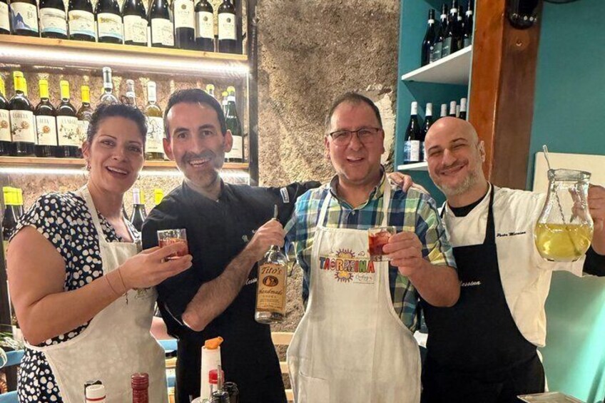 Cuatro personas en un bar, con botellas de vino al fondo. 2