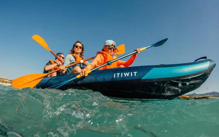 A group of people kayaking in a blue and black boat labeled "ITIWIT" on a body of water. 4
