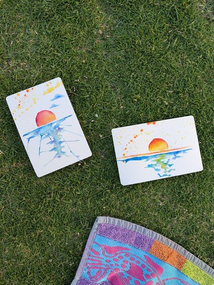 Two watercolor paintings of a sunset on grass. 3