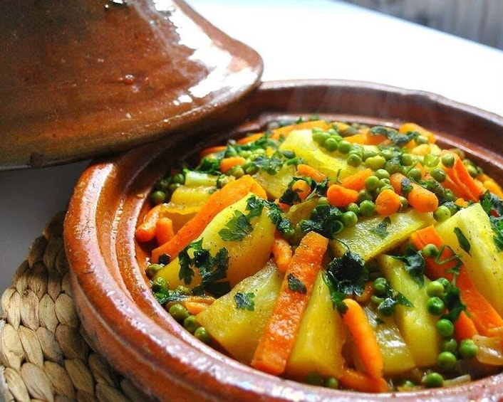 A tagine dish with vegetables like carrots, peas, and potatoes. 2