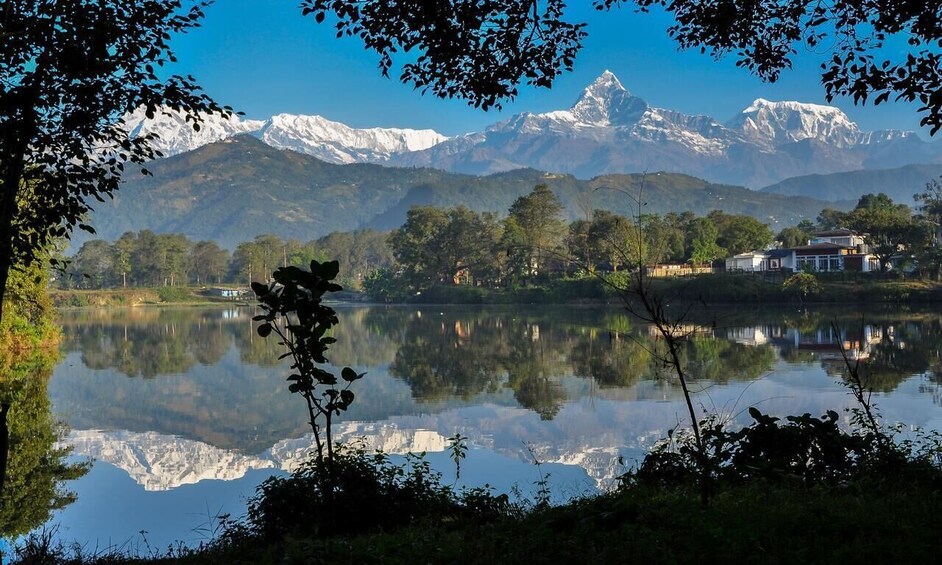 A calm lake reflecting mountains, trees, and a house. 3