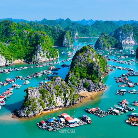 A coastal area with numerous boats docked at a pier, surrounded by lush green hills and rocky formations. 1