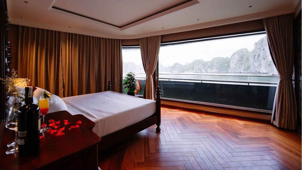A hotel room with a large bed, wooden flooring, a view of a river, and curtains. 5